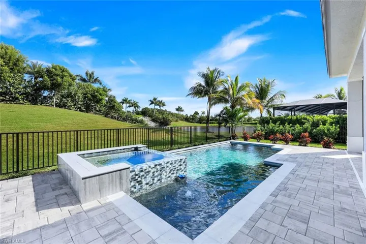 View of swimming pool featuring a patio area, a pool with connected hot tub, a fenced backyard, and a water view