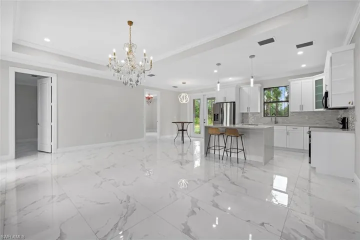 Kitchen with crown molding, appliances with stainless steel finishes, tile floor, a raised ceiling, and backsplash