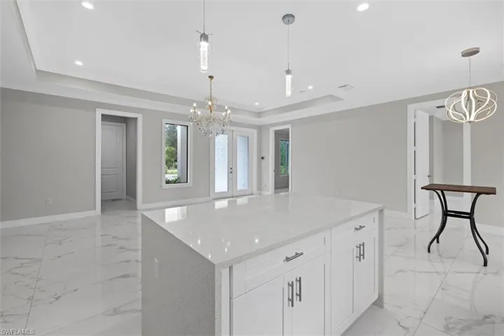 Kitchen with a tray ceiling, an inviting chandelier, tile floor, and recessed lighting