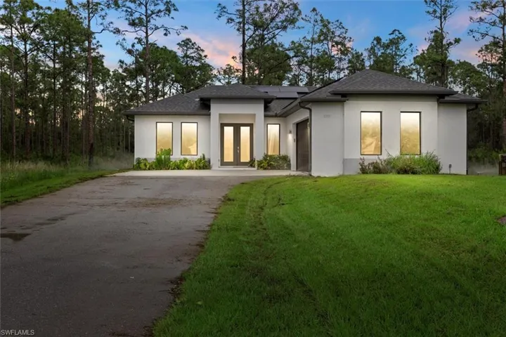 Modern Style house with solar panels, a yard, aphalt driveway, stucco siding, and french doors