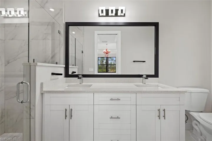 Primary bathroom with double vanity, a tile shower, two sink