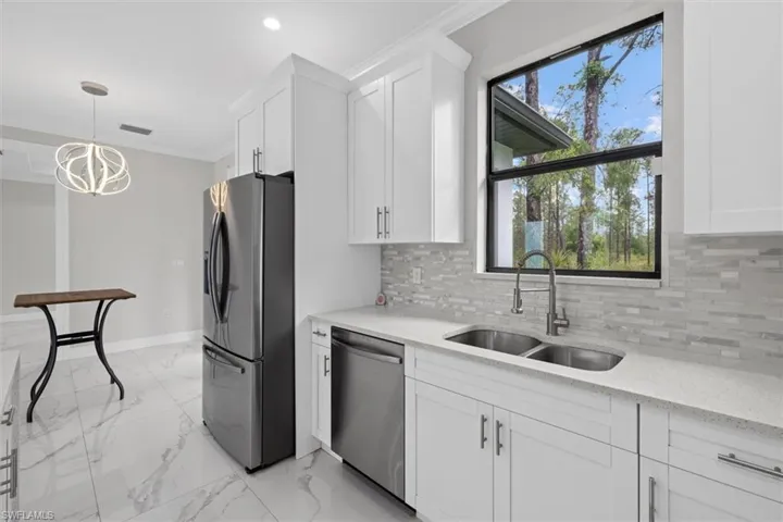 Kitchen with white cabinetry, crown molding, appliances with stainless steel finishes, tile floor, and a sink