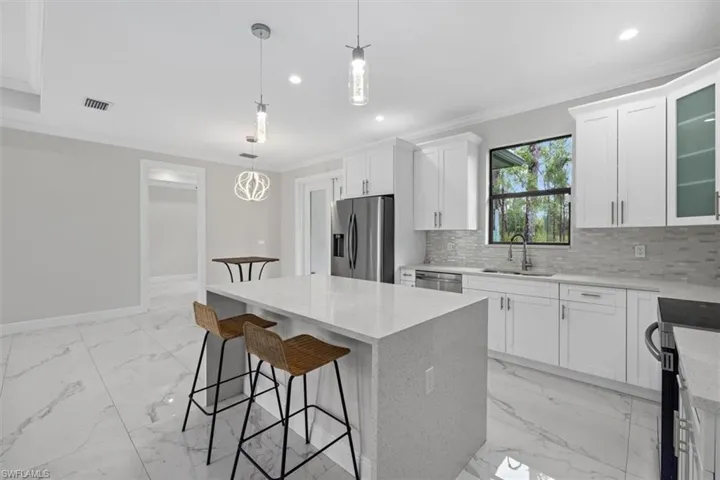 Kitchen with decorative backsplash, a sink, ornamental molding, and appliances with stainless steel finishes