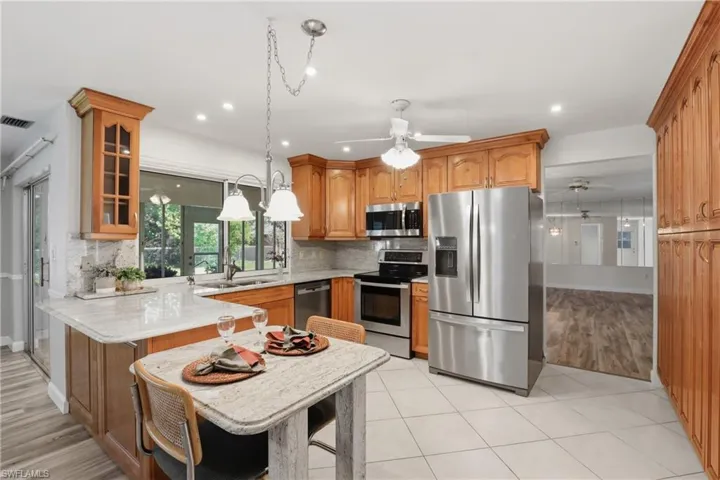 Light and cheerful kitchen featuring a breakfast bar, ample cabinetry, and a convenient serving window to the lanai.