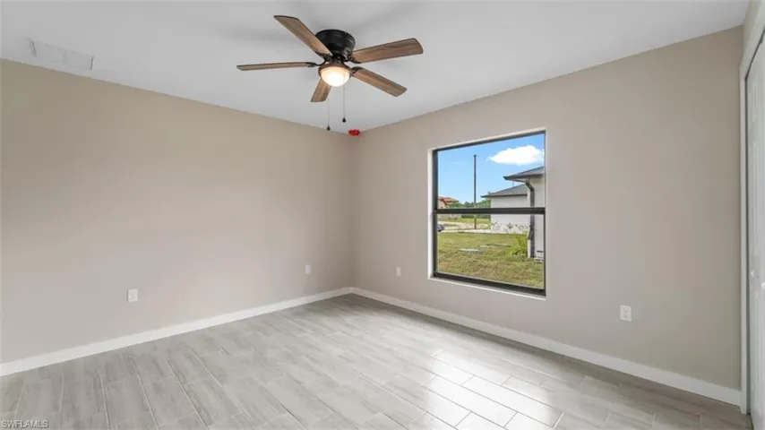 Spare room with a ceiling fan, visible vents, and baseboards