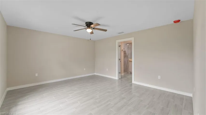 Spare room featuring a ceiling fan, visible vents, light wood-style flooring, and baseboards