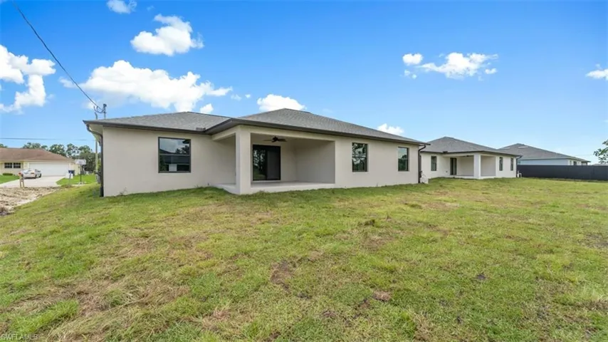 Rear view of house with a yard, a patio, and stucco siding