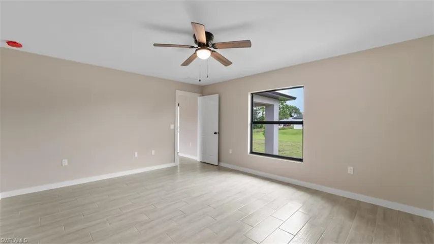 Unfurnished room with ceiling fan, light wood finished floors, and baseboards