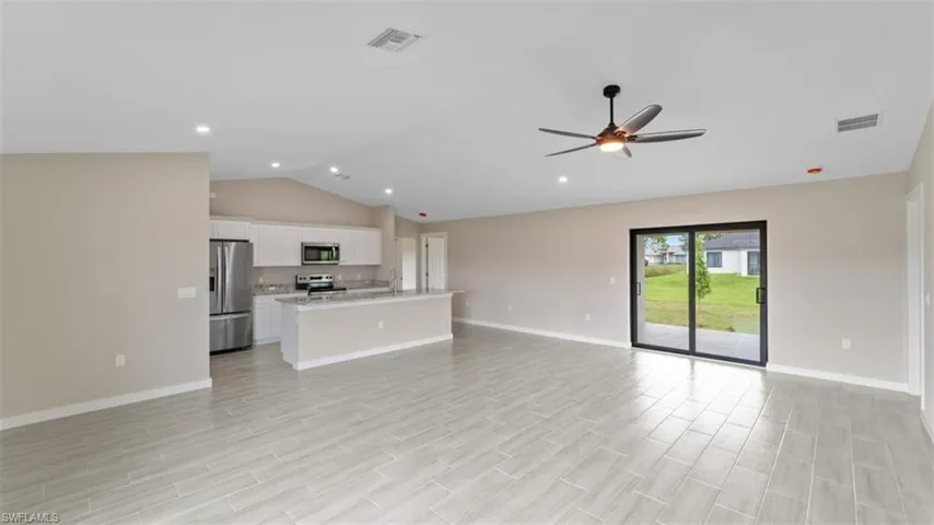 Unfurnished living room featuring visible vents, vaulted ceiling, and baseboards