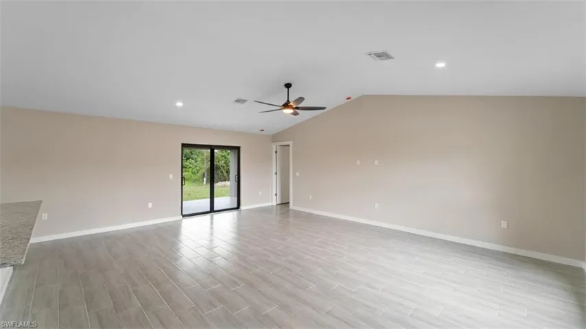 Unfurnished room with vaulted ceiling, ceiling fan, light wood finished floors, and visible vents