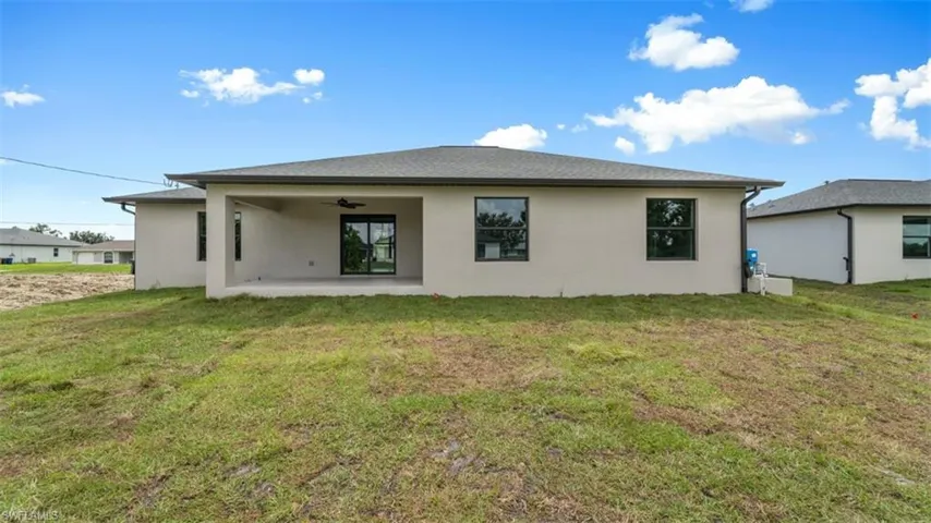 Rear view of property with a patio, a yard, a ceiling fan, and stucco siding