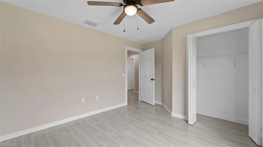 Unfurnished bedroom with a ceiling fan, visible vents, baseboards, a closet, and wood tiled floor
