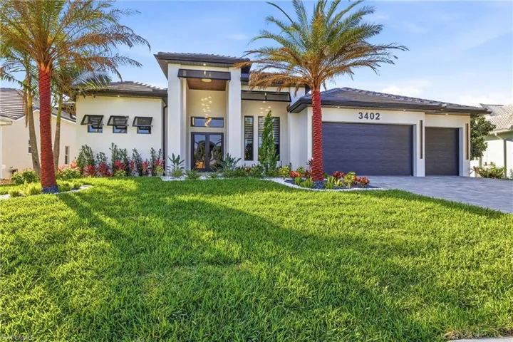 View of front facade with french doors, a front yard, stucco siding, and an attached garage