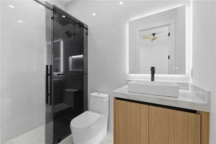Full bath with vanity, a shower stall, and ceiling fan