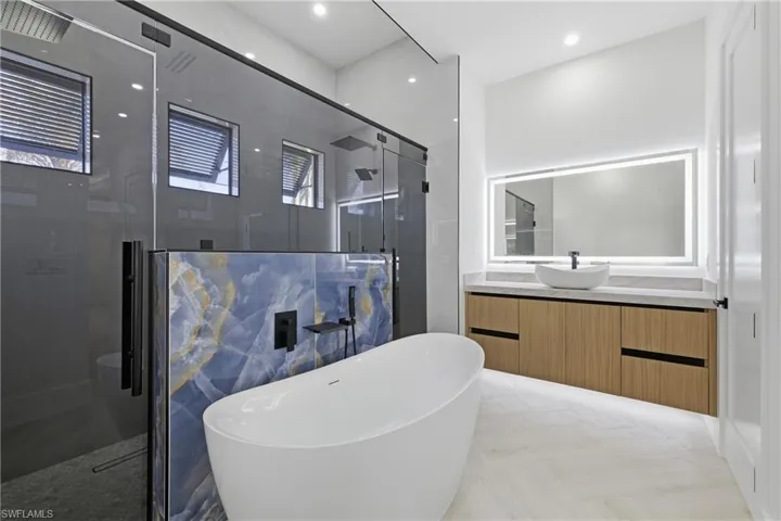 Full bathroom with vanity, a shower stall, a freestanding tub, and recessed lighting