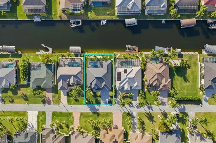 Aerial view of residential area featuring a nearby body of water and property parcel outlined