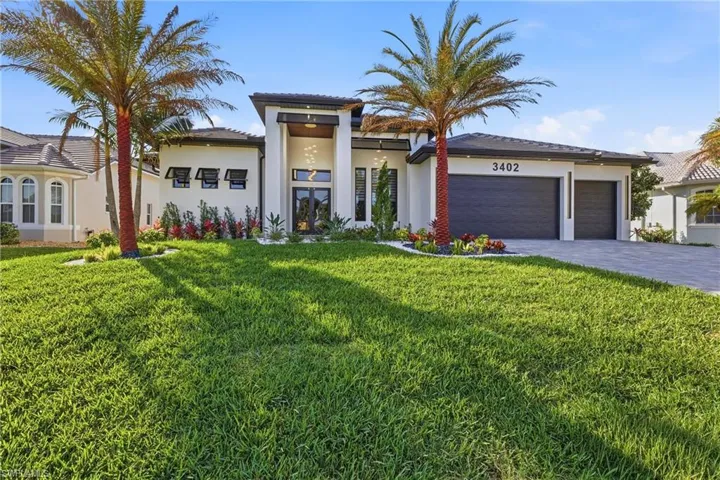 View of front facade featuring french doors, a front yard, stucco siding, an attached garage, and driveway