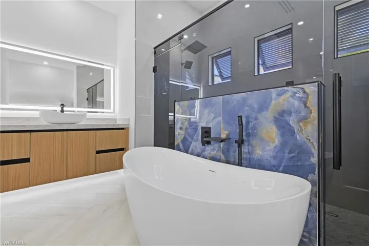 Full bathroom featuring vanity, a stall shower, and a soaking tub