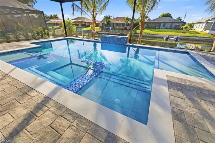 Combined pool / hot tub featuring a residential view, a water view, glass enclosure, and a sunroom