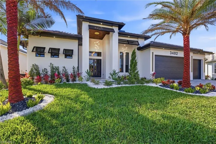 Contemporary house featuring a front yard, stucco siding, a garage, and driveway