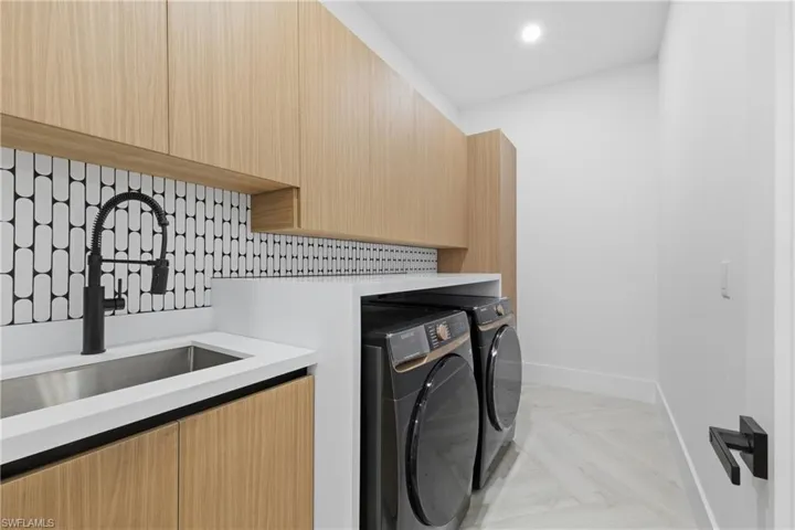 Laundry area featuring parquet flooring, washing machine and dryer, recessed lighting, and cabinet space