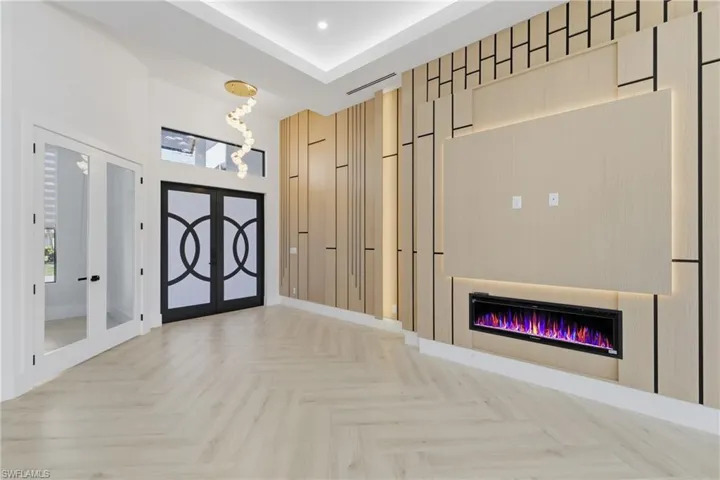 Entrance foyer with french doors, parquet flooring, and a glass covered fireplace