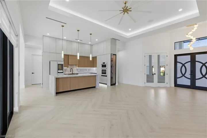 Dual tone kitchen with open floor plan, modern cabinets, french doors, a high ceiling, and decorative light fixtures