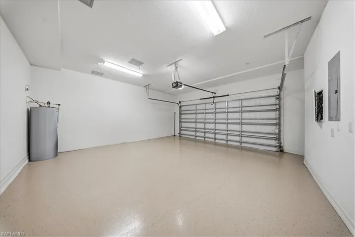 Garage featuring water heater, electric panel, and a garage door opener