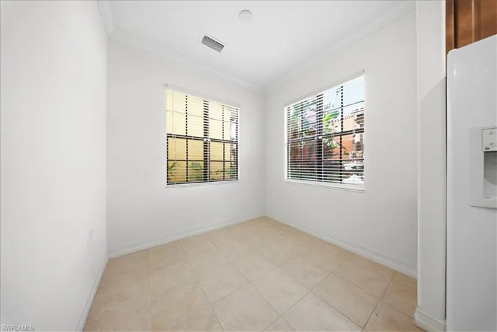 Unfurnished room with ornamental molding and light tile patterned flooring