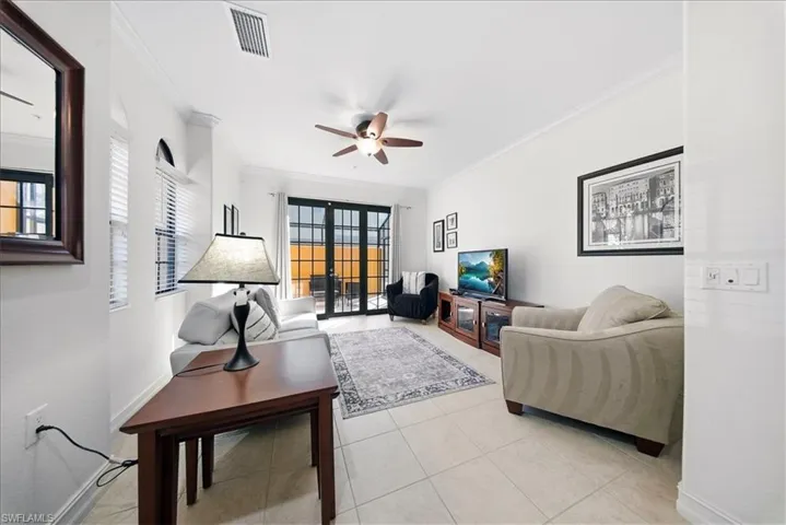 Living area featuring ornamental molding, ceiling fan, and light tile patterned flooring