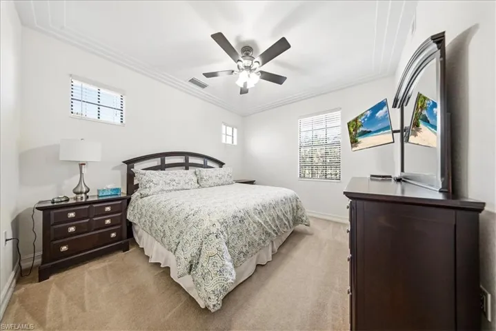 Bedroom with ceiling fan, light carpet, and ornamental molding