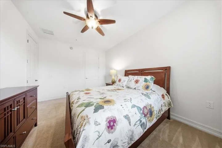 Bedroom featuring light carpet, ceiling fan, and vaulted ceiling