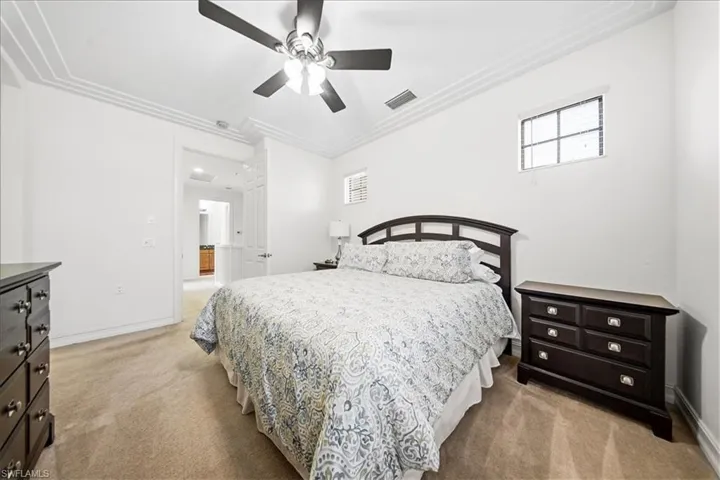 Bedroom featuring multiple windows, light carpet, ceiling fan, and ornamental molding