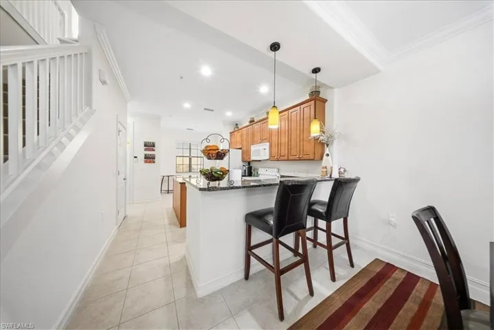 Kitchen featuring crown molding, a peninsula, a breakfast bar area, dark stone countertops, and wood finish cabinetry