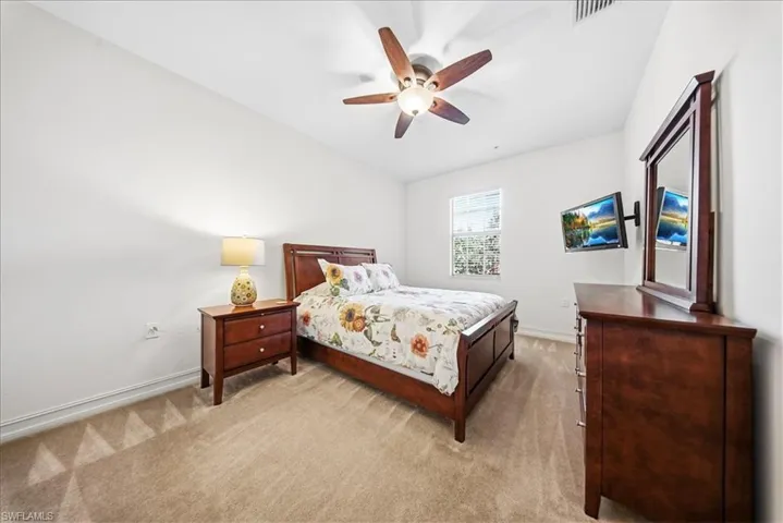 Bedroom with light colored carpet and a ceiling fan