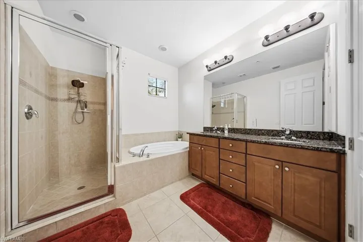Full bath with a shower stall, a garden tub, light tile patterned flooring, and double vanity