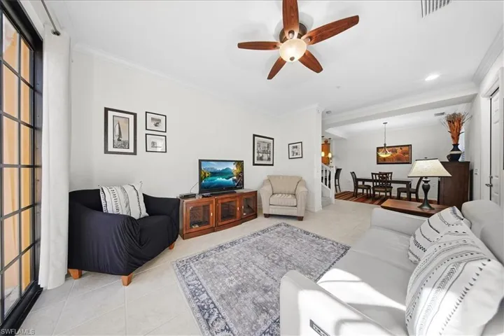 Living area featuring tile patterned floors, ornamental molding, and ceiling fan