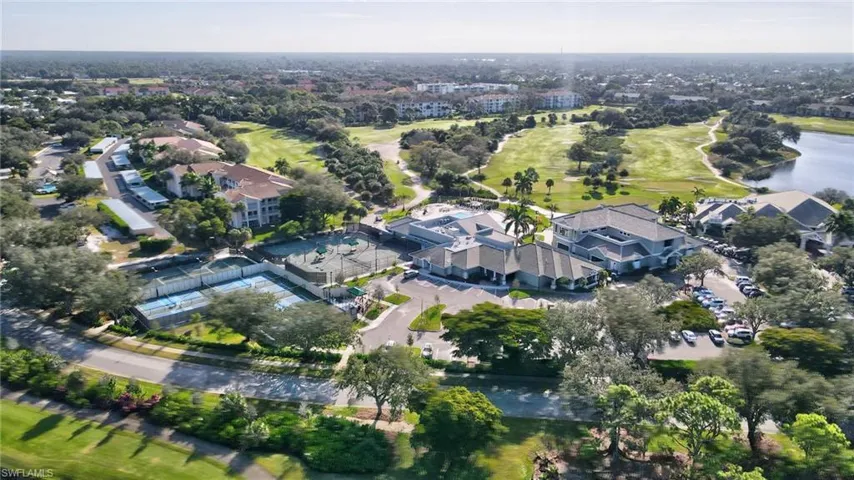 Aerial perspective showcasing a residential community with a large golf course, multiple tennis courts, and a central clubhouse structure