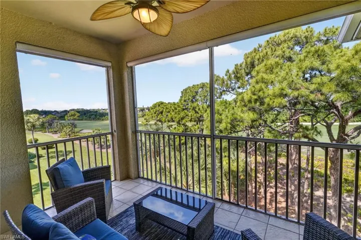 Screened outdoor balcony with a paddle-bladed ceiling fan, tile flooring, and metal railings