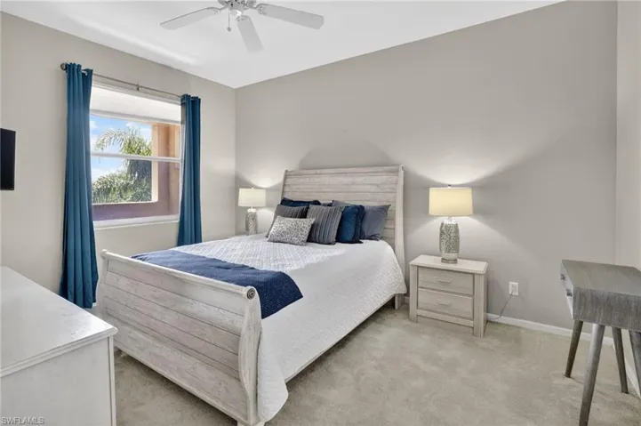 Carpeted room featuring a window with blue drapes, a ceiling fan, and light gray wall paint