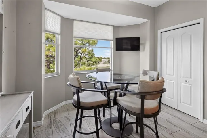 Bright dining nook featuring a bay window with natural light, wood-finish flooring, and a built-in closet with bi-fold doors
