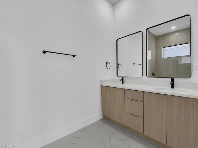 Bathroom featuring double vanity and light marble finish flooring