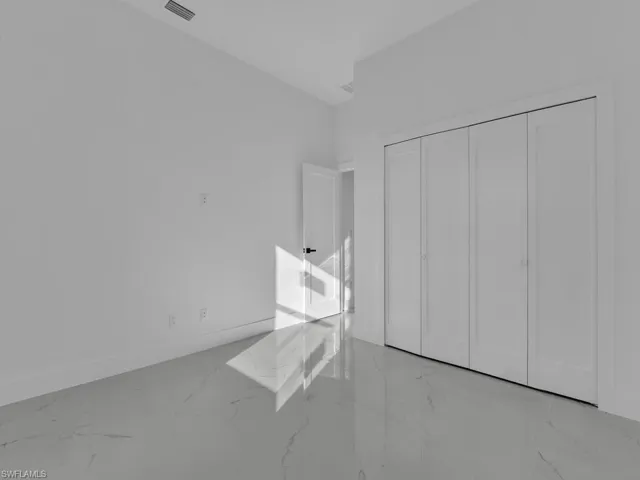 Unfurnished bedroom with light marble finish floors and a closet