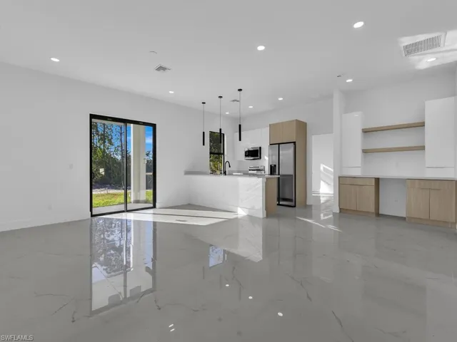 Unfurnished living room featuring light marble finish flooring and recessed lighting