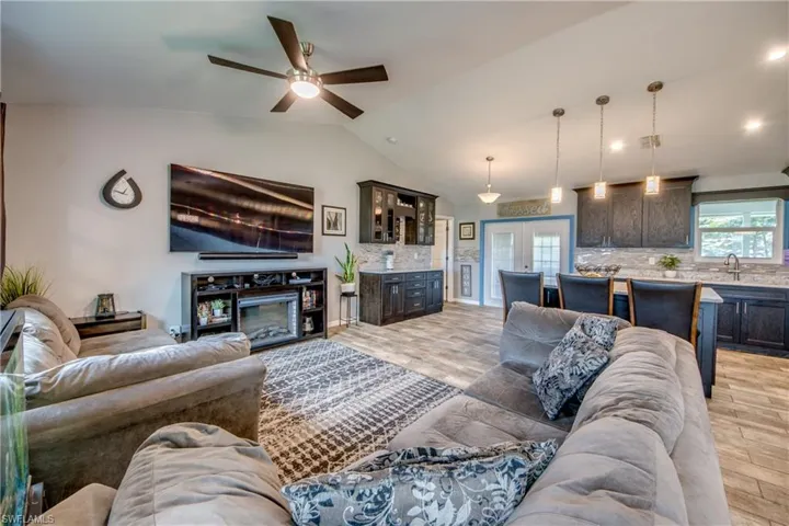 Living room with french doors, light hardwood / wood-style flooring, sink, ceiling fan, and vaulted ceiling