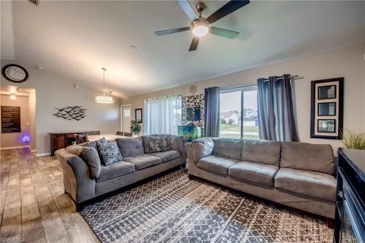 Living room featuring vaulted ceiling, hardwood / wood-style floors, and ceiling fan