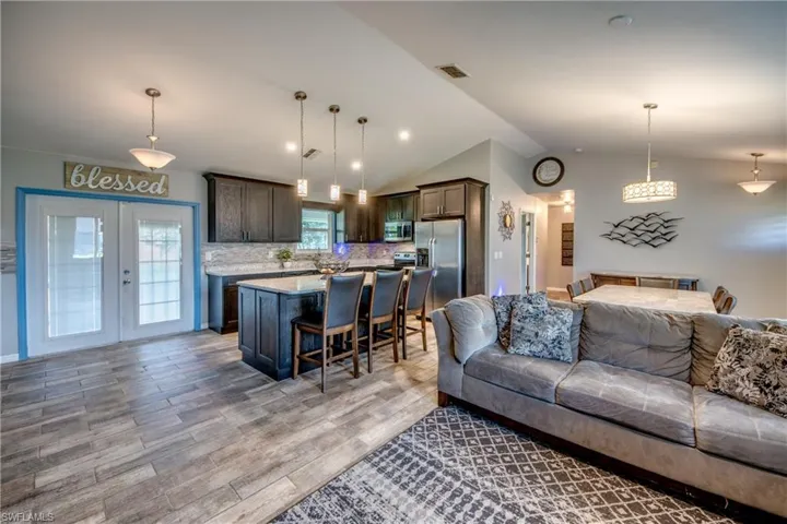Living room with vaulted ceiling, light hardwood / wood-style flooring, and french doors
