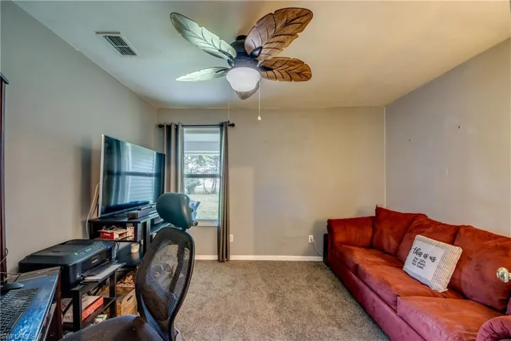 Carpeted home office featuring ceiling fan