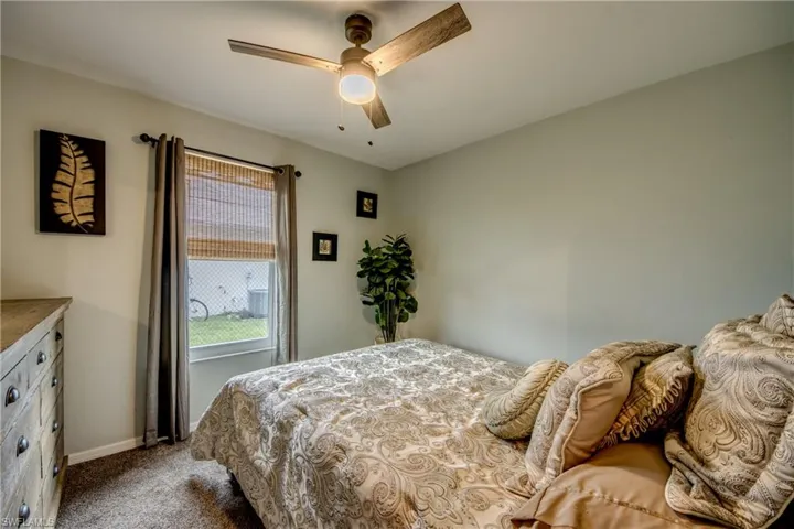 Carpeted bedroom featuring ceiling fan