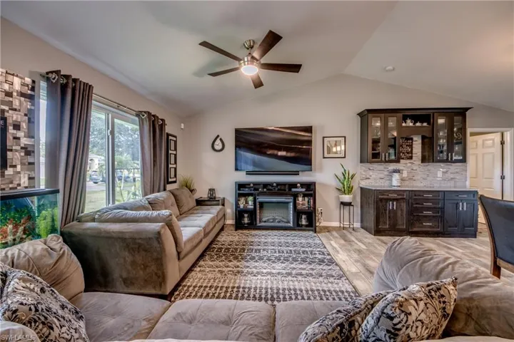 Living room featuring vaulted ceiling, ceiling fan, light hardwood / wood-style floors, and a fireplace